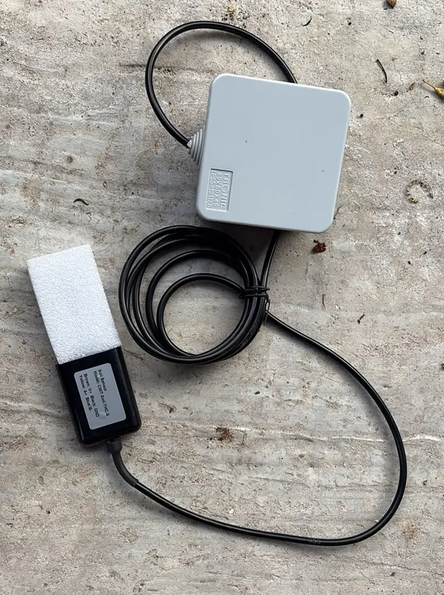 A NuaSense node box seen from above with its coiled cable and the soil sensor, its pins protected by white foam